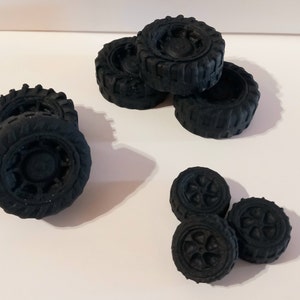 以下が含まれることがあります： 詳細なトレッドパターンとホイールデザインを備えた、小さな黒いおもちゃのタイヤのコレクション。 タイヤはいくつかのグループに配置され、サイズと形状を示しています。 全体的な美しさはマット仕上げで、タイヤの質感が強調されています。