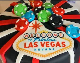 Può includere: Una torta decorata con fiches da casinò colorate, tra cui verde, rosso, blu e nero. La torta ha una base nera con strisce rosse e bianche e un cartello con la scritta "Welcome to Fabulous Las Vegas Nevada."