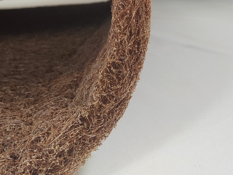 May include: Close-up of a rolled, textured brown material. The material appears to be made of interwoven fibers, creating a rough, organic texture. The color is a warm, earthy brown, with variations in tone. The material is likely used for crafts or home decor.