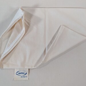 May include: A white pillowcase with a zipper closure and a blue label that reads "speltex das liegt mir".