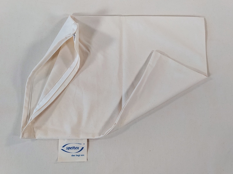 May include: A white pillowcase with a zipper closure and a blue label that reads "speltex das liegt mir".