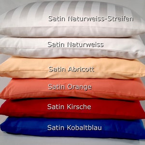 Könnte beinhalten: Ein Stapel von sechs Kissenbezügen in verschiedenen Farben, darunter Weiß, Pfirsich, Orange, Rot und Blau. Die Kissenbezüge sind mit dem Stofftyp und der Farbe gekennzeichnet, z. B. "Satin Naturweiss-Streifen" und "Satin Kobaltblau".