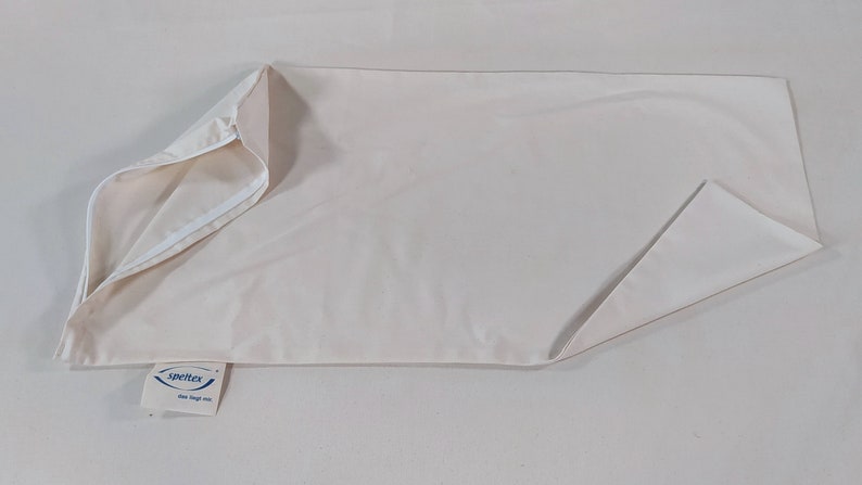 May include: A white pillowcase with a zipper closure. The pillowcase is made of a soft, breathable fabric. The brand name "Spettex" is printed on a blue tag attached to the pillowcase.