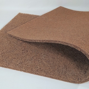 May include: Two brown, rectangular mats with a textured, fibrous surface. One mat is partially lifted, revealing the texture and thickness of the material. The mats are set against a white background.