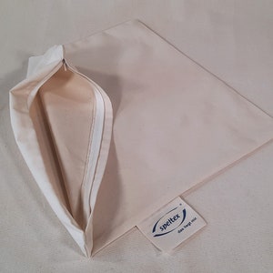 May include: A beige pillowcase with a zipper opening. The pillowcase has a white label with the text "spelltex das liegt mir."