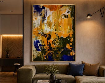 May include: A large rectangular abstract painting featuring thick, textured brushstrokes in vibrant shades of yellow, orange, deep blue, and dark green, framed in a thin gold border and displayed on a neutral wall above a low-profile olive sofa.