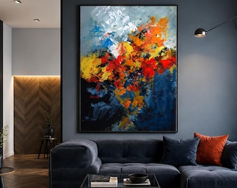 May include: A large rectangular abstract painting featuring thick, textured brushstrokes in vibrant shades of orange, red, yellow, white, and deep blue, displayed in a black frame on a dark gray wall above a navy blue sectional sofa.
