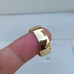 Op de afbeelding: Een gouden trouwring met een gepolijste afwerking.