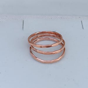 Peut inclure: Trois anneaux fins en cuivre martel&eacute; empil&eacute;s les uns sur les autres. Les anneaux sont d'une couleur or rose chaude.