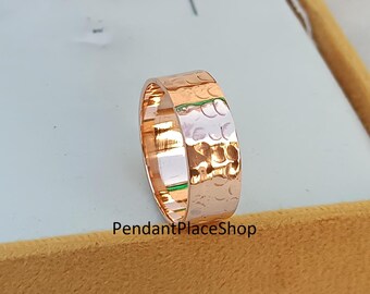 Op de afbeelding: Een gehammerde bandring van roségoud. De ring is breed en heeft een getextureerd oppervlak.