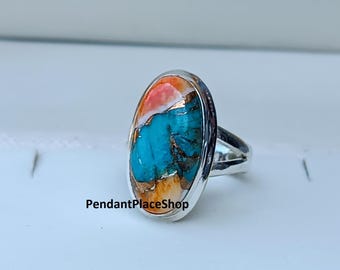 May include: Oval-shaped ring with a silver band. The ring features a vibrant stone with a mix of turquoise, orange, and white colors. The text "PendantPlaceShop" is visible on the ring.