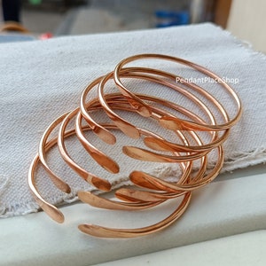May include: A set of six copper bangles stacked on top of each other. The bangles are all the same size and have a smooth, polished finish. The text "PendantPlaceShop" is visible on the top bangle.