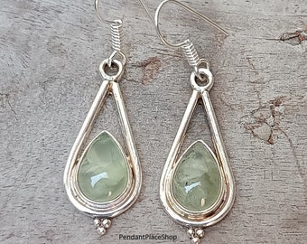 Puede incluir: Un par de pendientes de plata en forma de lágrima con detalles de piedras preciosas verdes. Los pendientes tienen un diseño delicado y calado y presentan un pequeño detalle de cuentas en la parte inferior.