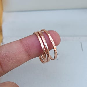 Peut inclure: Trois fines bagues empilables en or rose martel&eacute;. Les bagues sont port&eacute;es sur un doigt.