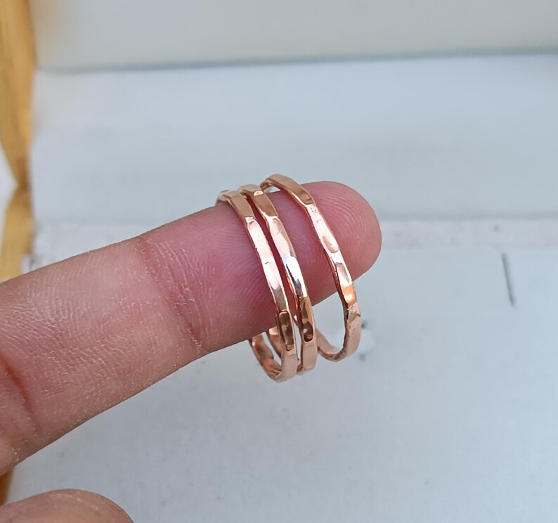 Peut inclure: Trois fines bagues empilables en or rose martel&eacute;. Les bagues sont port&eacute;es sur un doigt.