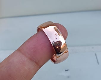 May include: A hammered copper wedding band ring with a polished finish.