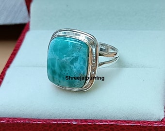 Könnte beinhalten: Ein silberner Ring mit einem quadratischen, hellblauen Edelstein. Der Ring ist in einer silbernen Band mit einem strukturierten Design gefasst. Der Text "Shreejaipuring" ist auf dem Ring sichtbar.