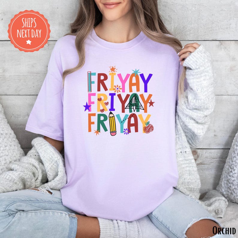 A woman wearing a pink t-shirt with a colorful graphic design that says "FRYAYAY FRYAYAY FRYAYAY" printed on it.