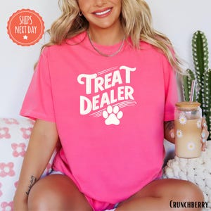 a woman wearing a pink shirt with a dog paw on it