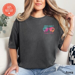 A woman wearing a black t-shirt with a graphic design on the front, sitting on a couch.