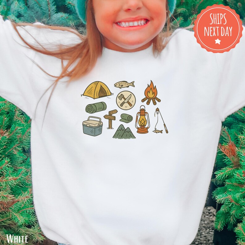 a little girl wearing a t - shirt with camping icons on it