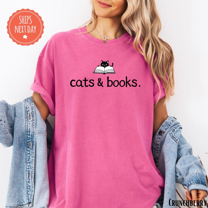 a woman wearing a pink shirt that says cats and books