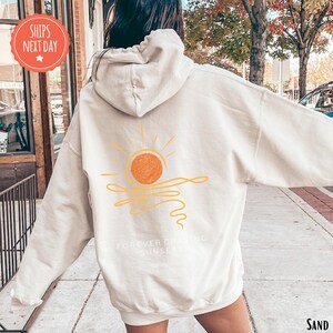 a woman walking down a sidewalk wearing a white hoodie