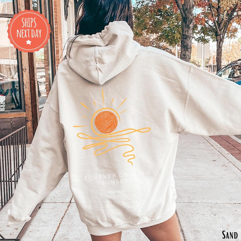 a woman walking down a sidewalk wearing a white hoodie