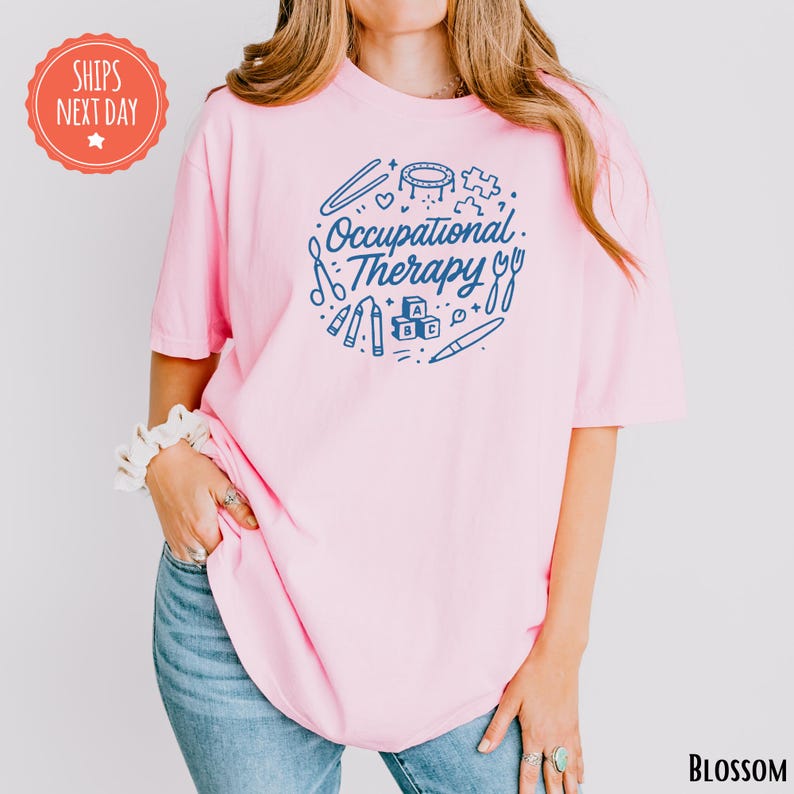 A woman wearing a pink t-shirt with the text "Occupational Therapy" printed on it, standing against a white background.