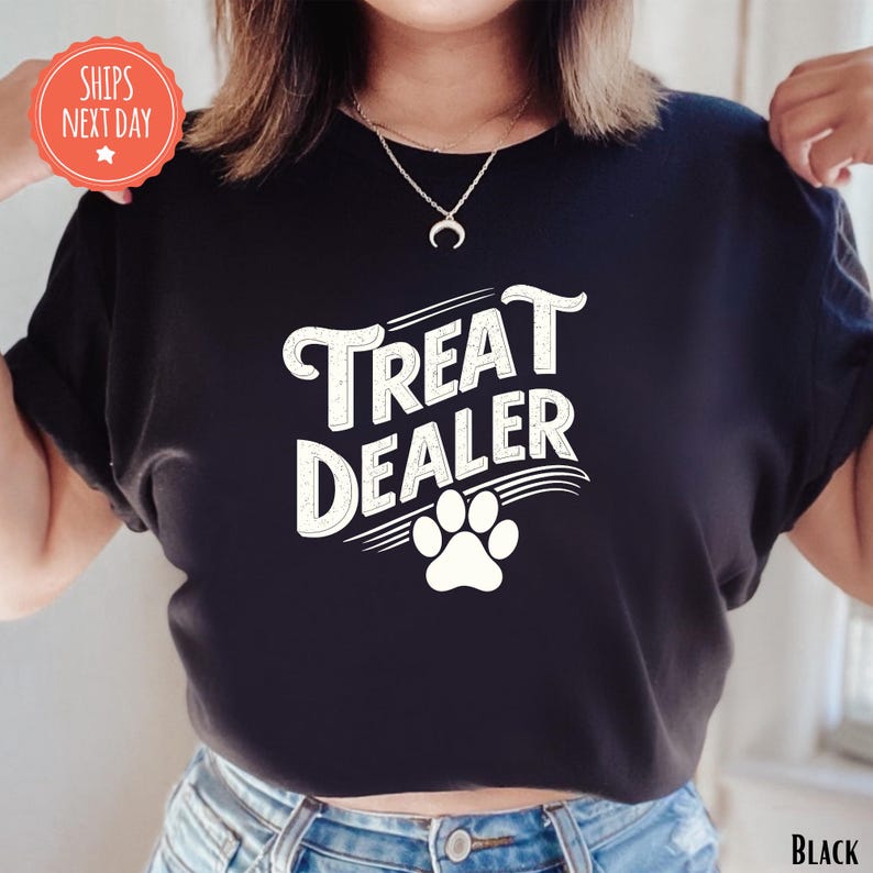 K&ouml;nnte beinhalten: Schwarzes T-Shirt mit dem Text "Treat Dealer" in wei&szlig;er, stilisierter Schrift und einem wei&szlig;en Pfotenabdruck. Das Shirt hat einen Rundhalsausschnitt und kurze &Auml;rmel. Der Text "Ships Next Day" befindet sich in einem roten Kreis.