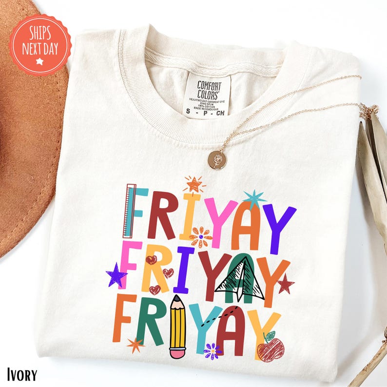 a white t-shirt with a colorful graphic design that says "FRYAYAY FRYAYAY" and includes various shapes and symbols such as a pencil, star, and apple.