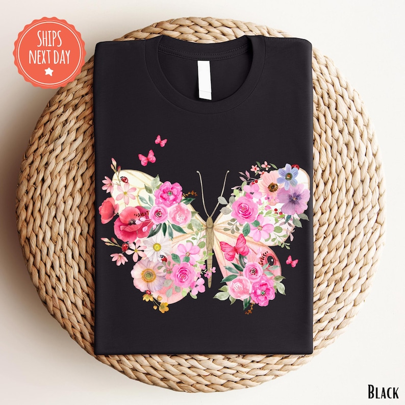A black t-shirt with a colorful floral butterfly design printed on it, placed on a woven placemat.