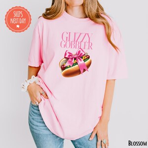 a woman wearing a pink shirt with a hot dog on it