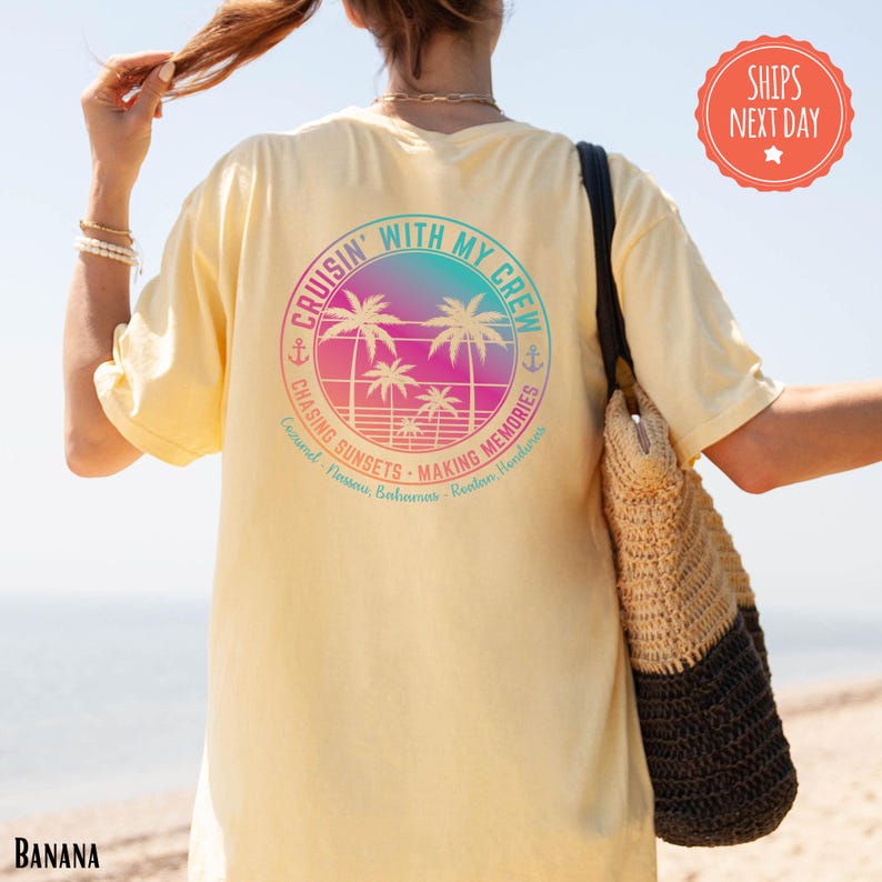A person wearing a yellow t-shirt with a graphic design of palm trees and a beach scene, standing on a beach with their hair in a ponytail.