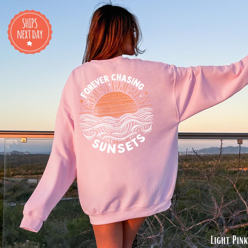 a woman wearing a pink sweatshirt that says forever chasing sunsets