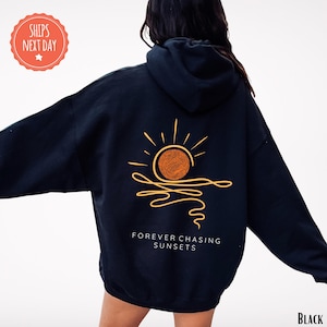 a woman wearing a black hoodie with a sun on it