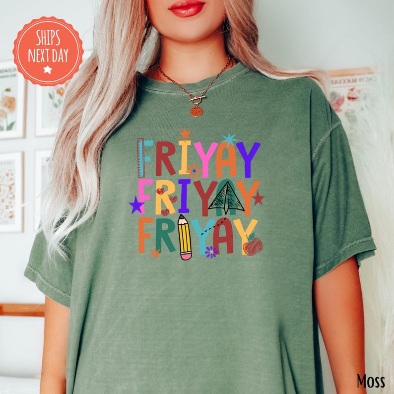 A woman wearing a green t-shirt with a colorful graphic design that says "FRIDAY FRIDAY" and includes various icons and illustrations.