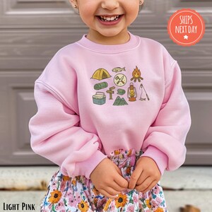 a little girl wearing a pink sweatshirt and shorts