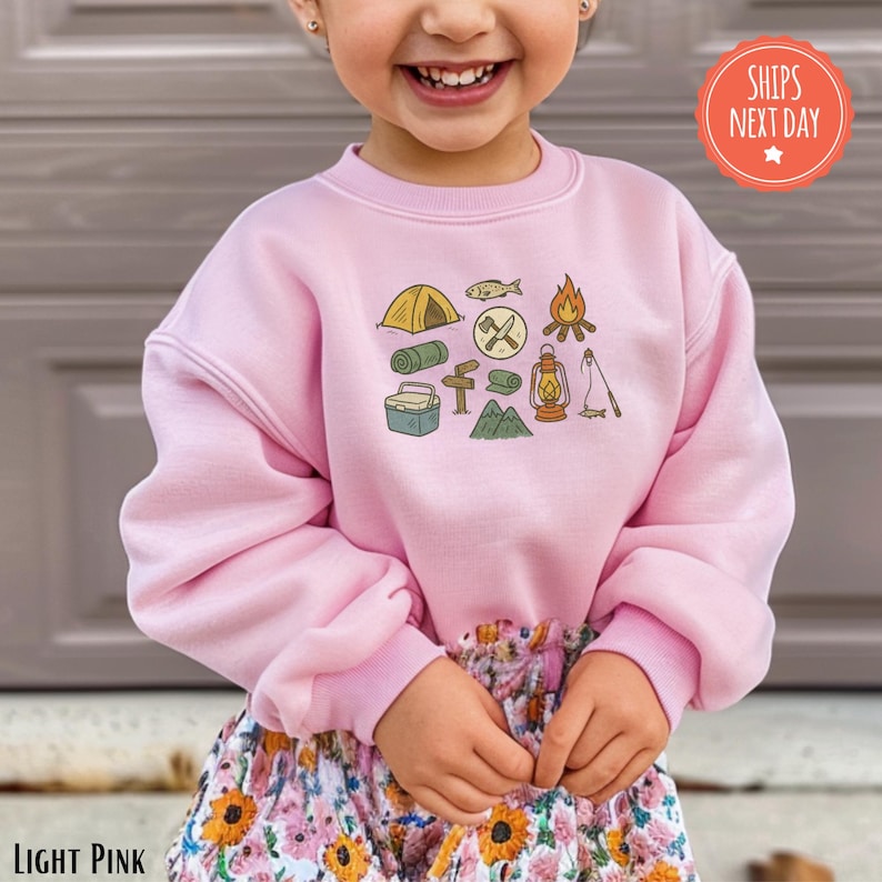 a little girl wearing a pink sweatshirt and shorts
