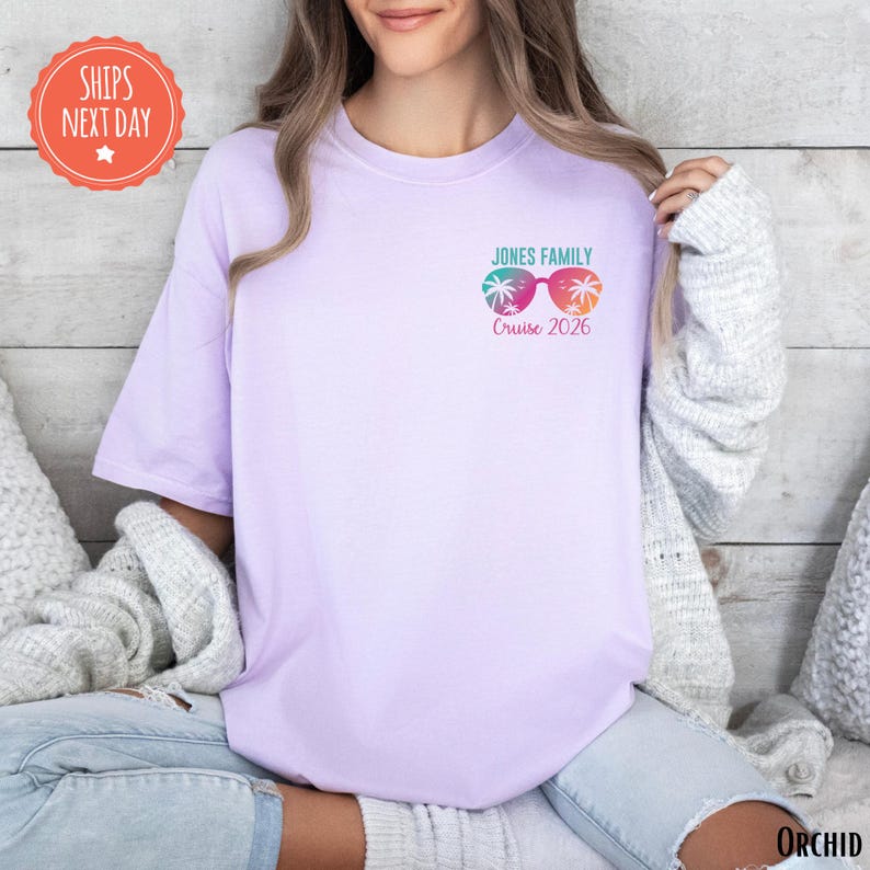 A woman wearing a purple t-shirt with a graphic design and text on it, sitting on a couch.