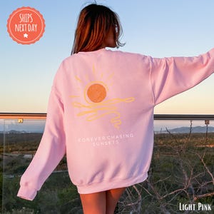 a woman wearing a pink sweatshirt with a sun on it