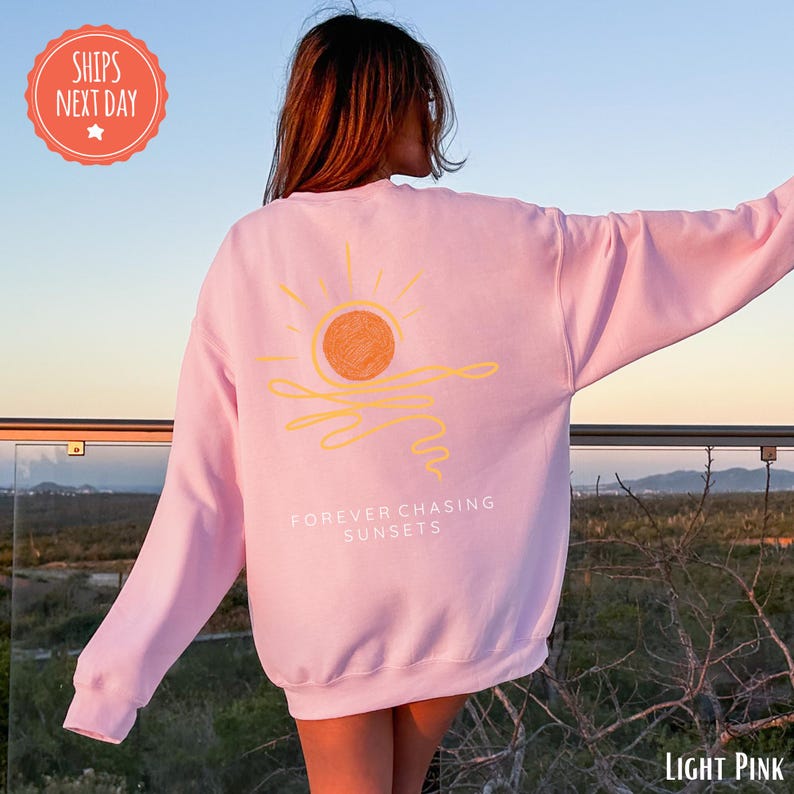 a woman wearing a pink sweatshirt with a sun on it