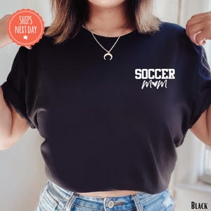 A person wearing a black t-shirt with the text "SOCCER MOM" printed on it.