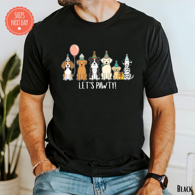 A black t-shirt with a graphic design of six dogs wearing party hats and the text "Let's PAWTY!"