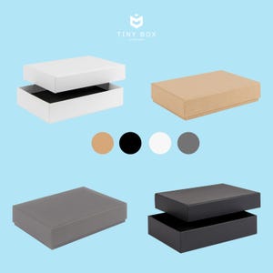 May include: Four different gift boxes with lids. The boxes are in white, brown, grey, and black. The boxes are all the same size and shape. The boxes are ideal for packaging small gifts.