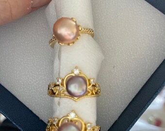 May include: Three gold rings with pearl accents. The top ring has a single pearl, the middle ring has a pearl in a crown setting, and the bottom ring has a pearl in a crown setting with smaller stones.