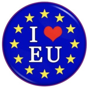 以下が含まれることがあります： 青い丸いバッジで、白い「I EU」の文字、赤いハート、黄色の星が円形に配置されています。 バッジにはピンク色の縁取りと光沢のある仕上げが施されています。