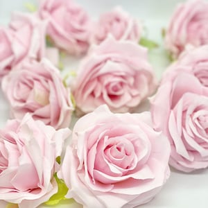 Könnte beinhalten: Eine Ansammlung von künstlichen, blassrosa Rosen, die in Herzform angeordnet sind, vor einem weißen Hintergrund.