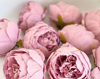 Op de afbeelding: Een groep van 10 stoffige roze zijden pioenen. De pioenen zijn in een cluster gerangschikt, met sommige overlappend. De pioenen zijn allemaal scherp en hebben een zachte, fluweelachtige textuur.