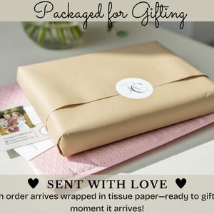 May include: A gift wrapped in brown paper, secured with twine and a white sticker. The package rests on a pink bubble mailer, with a card featuring a family photo. Text reads "Packaged for Gifting" and "Sent with Love."